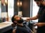 A barber trimming a client's beard with a precision trimmer beside a barbershop sink station