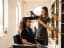 A stylist blow-drying a client's hair with a round brush in a bright, plant-filled salon
