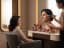 A makeup artist applying blush to a client's cheek at a mirrored vanity